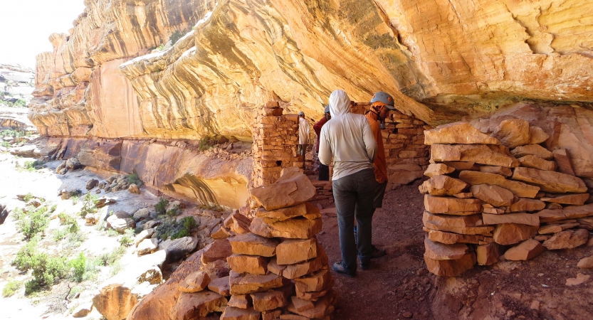 Two people explore an old dwelling built into a rock wall.